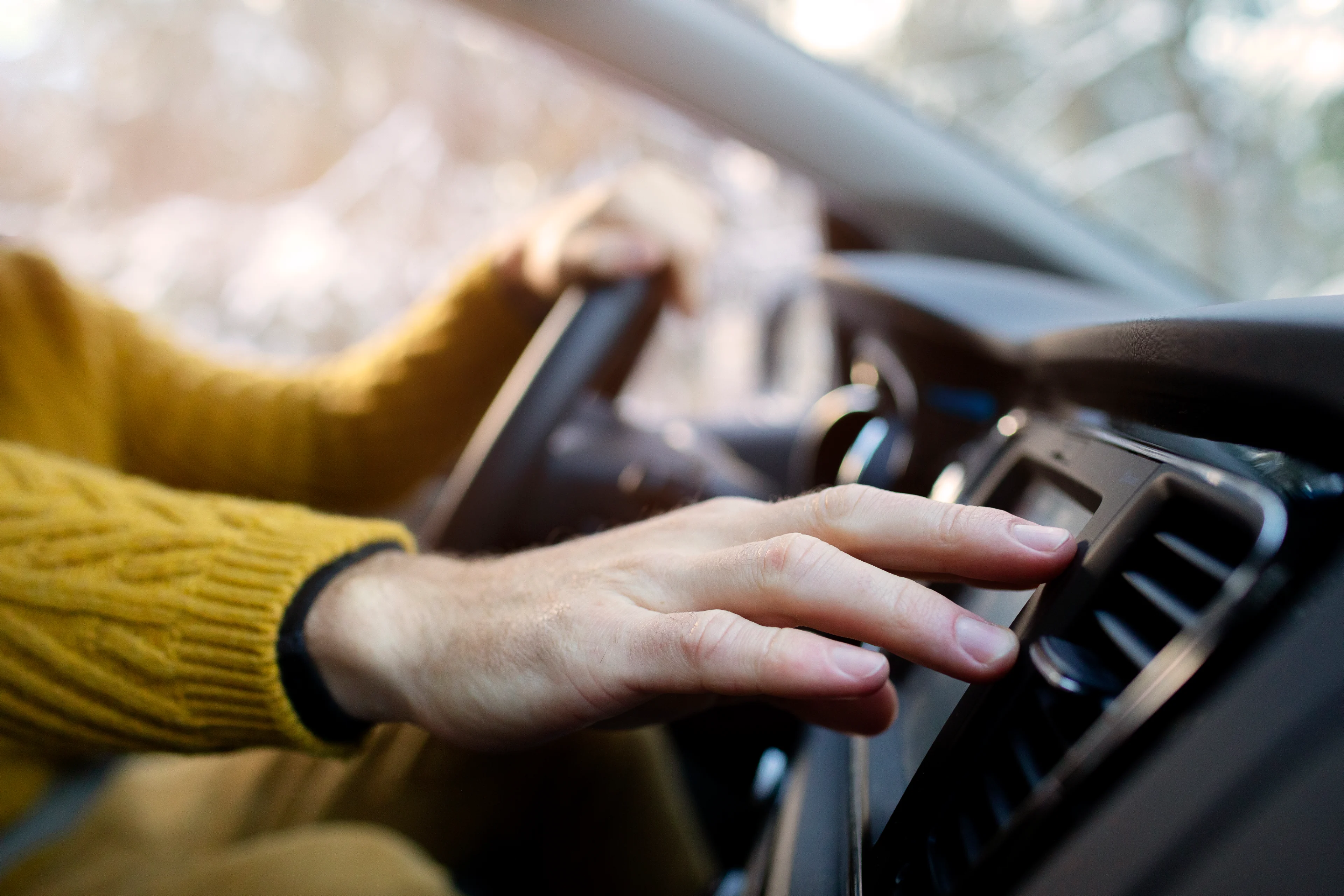 person som håller högra handen över fläktutblåset i bilen
